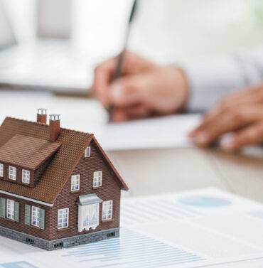Real estate agent working in his office, reviewing property listings and taking notes on a computer desk
