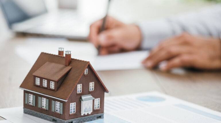 Real estate agent working in his office, reviewing property listings and taking notes on a computer desk