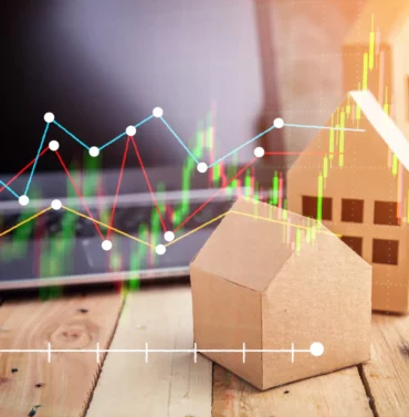 Real estate documents, keys, and a house model placed on a wooden floor, symbolizing home buying or selling process