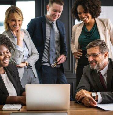 Team of professionals collaborating and discussing on a laptop in a modern office setting