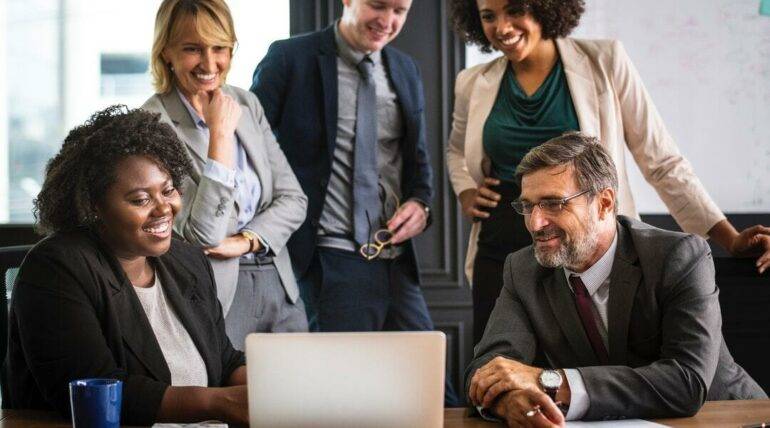 Team of professionals collaborating and discussing on a laptop in a modern office setting