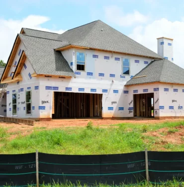 New home construction site with wooden framing and building materials under a clear sky